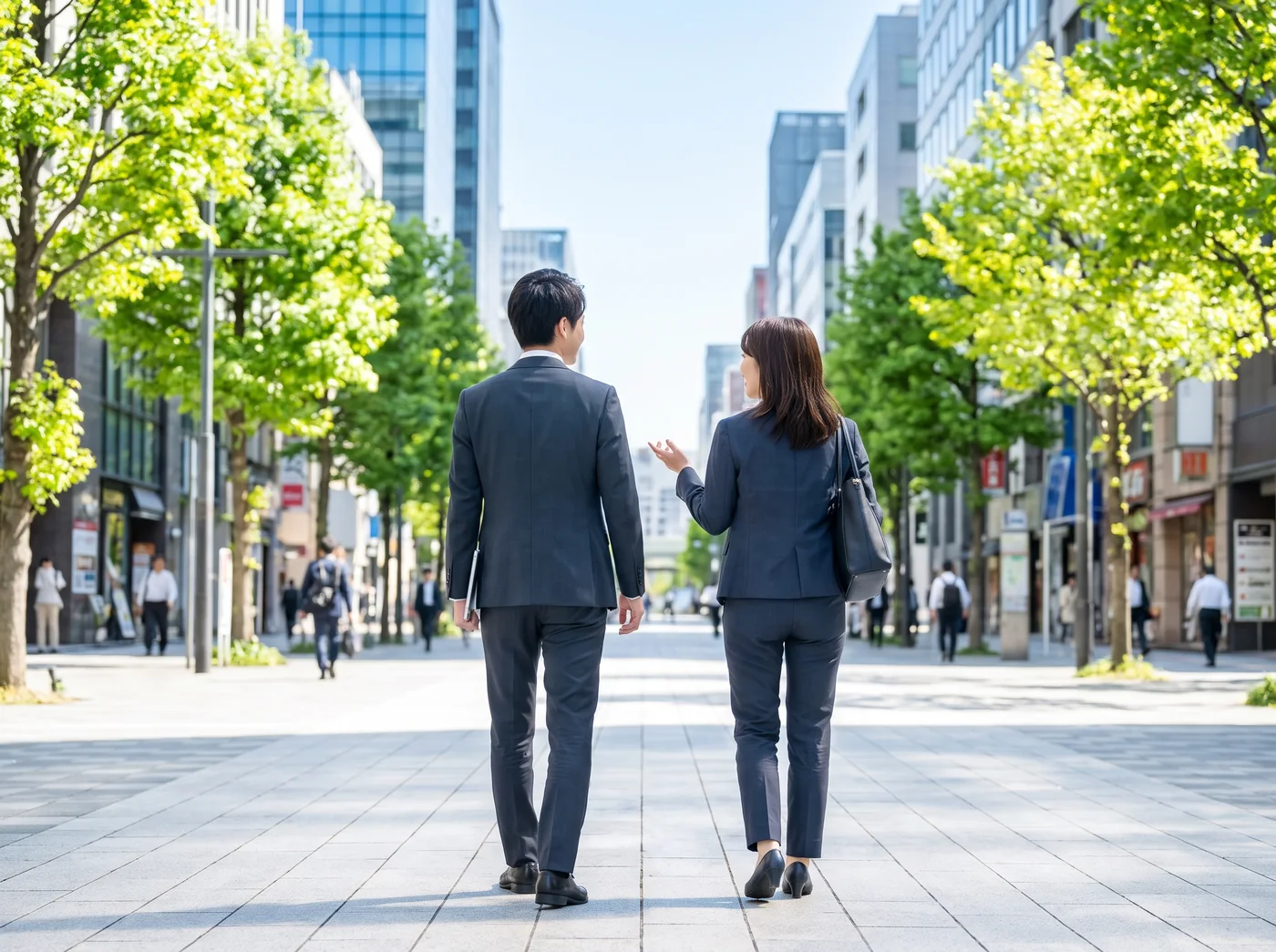 スーツ姿で並んでオフィス街を歩く営業社員2人の後ろ姿