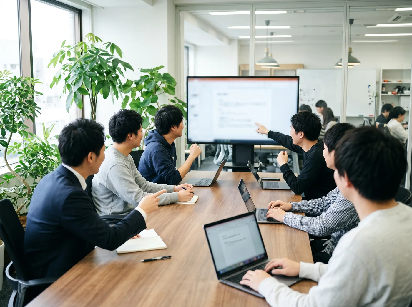 オフィスでエンジニアチームと笑顔で話し合う営業社員